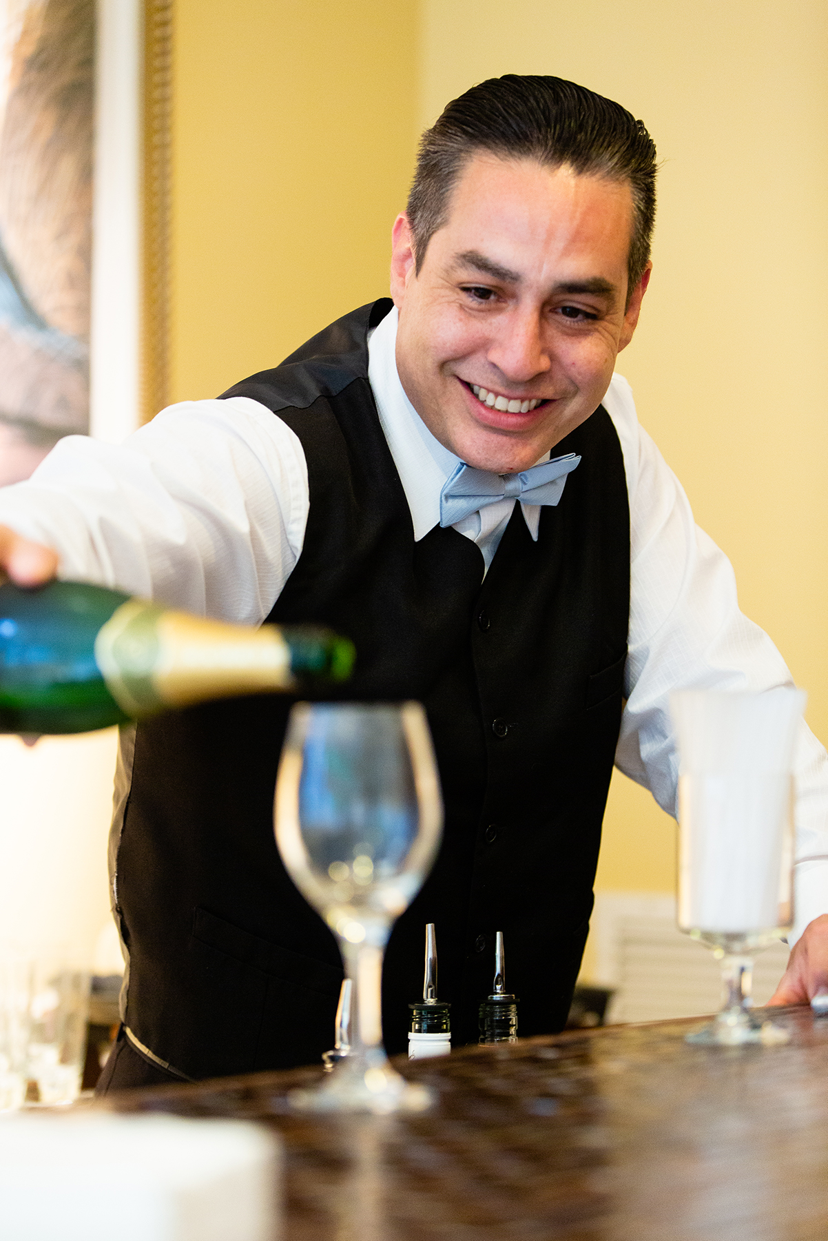 Smiling waiter pouring wine.